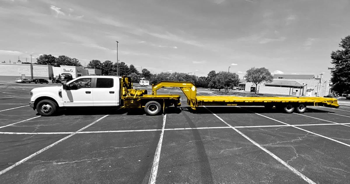 Hotshot pickup truck pulling a long gooseneck flatbed trailer.